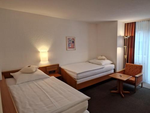 a hotel room with two beds and a chair at Hotel Gerberhof in Backnang