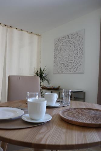 a wooden table with plates and cups on it at La Petite Boire - Chambres d'hôtes près d'Angers in Mûrs-Érigné