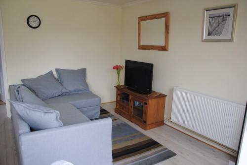 uma sala de estar com um sofá e uma televisão em Holiday chalet Cowes Isle of Wight em Gurnard