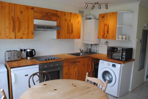 uma cozinha com armários de madeira, uma mesa e uma máquina de lavar roupa em Holiday chalet Cowes Isle of Wight em Gurnard