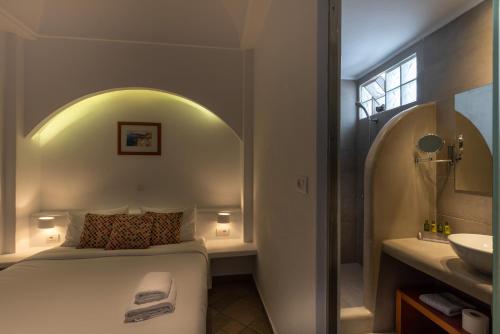 a bedroom with a bed and a bathroom with a sink at Anamnesis City Spa in Fira