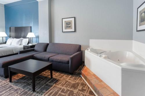 a hotel room with a couch and a bed and a tub at La Quinta by Wyndham Kerrville in Kerrville