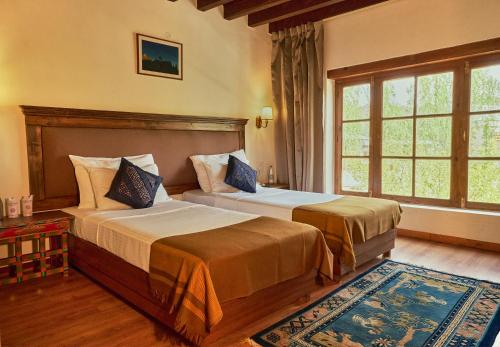 a bedroom with two beds and a large window at Hotel Kang Lha Chen in Leh