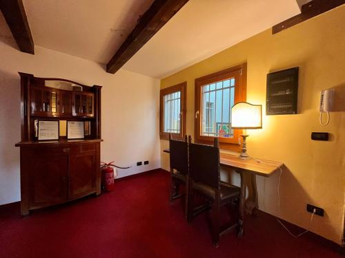 Zimmer mit einem Schreibtisch, einer Lampe und Fenstern in der Unterkunft Ai Boteri in Venedig