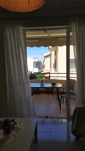 a living room with a view of a patio with a table at Marilena's Apartment in Rafina