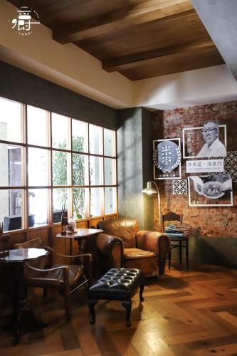 a living room with a couch and tables and windows at Roots Chew Hotel in Tainan