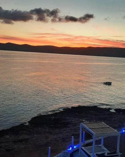 a boat in a body of water at sunset at En plo villa Sounio in Sounio