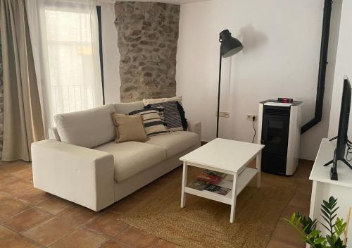 ein Wohnzimmer mit einem weißen Sofa und einem Tisch in der Unterkunft Apartamento con encanto en el Pirineo in La Pobla de Lillet