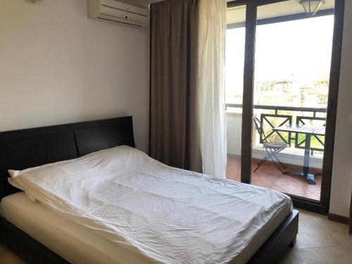 een bed in een slaapkamer met uitzicht op een balkon bij Oasis Resort & Spa Cozy Studio in Lozenets