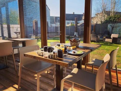 une salle à manger avec une table, des chaises et une grande fenêtre dans l'établissement B&B L'Echappée Belle, à Falaën