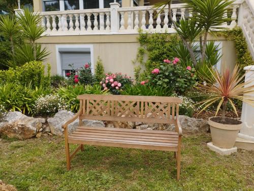 a wooden bench sitting in a yard with flowers at Villa Flora Superior Apartment in Cabris