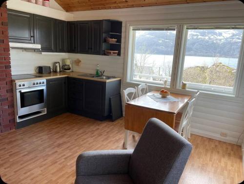a kitchen with black cabinets and a table with chairs at Vettinghytta, close to the sea with amazing view. in Gravdal