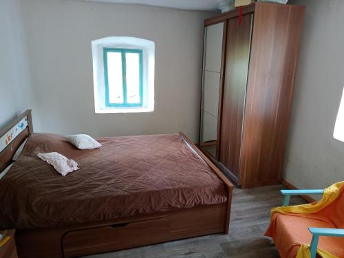 1 dormitorio con 1 cama, armario y ventana en Country stone house Kovacevic, en Danilovgrad