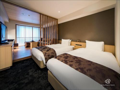a hotel room with two beds and a flat screen tv at Daiwa Roynet Hotel Kyoto Ekimae PREMIER in Kyoto
