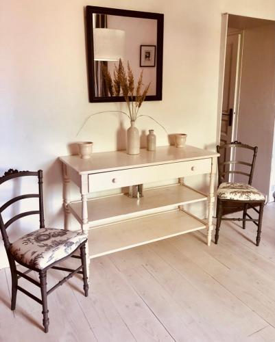 a white console table with two chairs and a mirror at LA PARENTHÈSE in Saubrigues