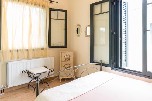 a bedroom with a bed and a chair and windows at Koni's House in Meganisi