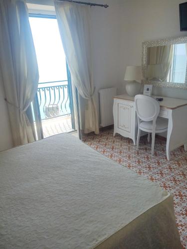 a bedroom with a bed and a desk and a mirror at Hotel La Perla in Praiano