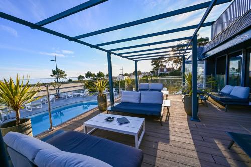 a patio with blue furniture and a swimming pool at Le Diana Hôtel & Spa NUXE in Carnac