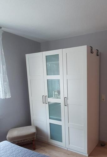 a bedroom with a white cabinet and a chair at Ferienwohnung Waldblick in Brilon