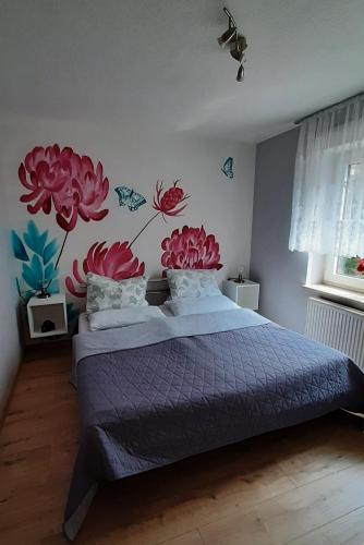 a bedroom with a bed with flowers painted on the wall at Ferienwohnung Waldblick in Brilon