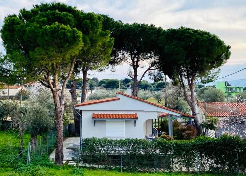 uma pequena casa branca com árvores atrás de uma cerca em Casa Annie em Loutraki