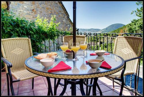a table with wine glasses and food on a balcony at La Borda de Mery. in Charo