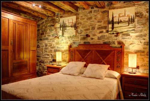 a bedroom with a bed in a stone wall at La Borda de Mery. in Charo