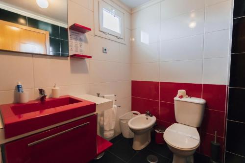 a bathroom with a red sink and a toilet at Quintas do Mar I in Ribeira Grande
