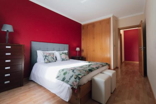 a bedroom with a large bed and a red wall at Quintas do Mar I in Ribeira Grande