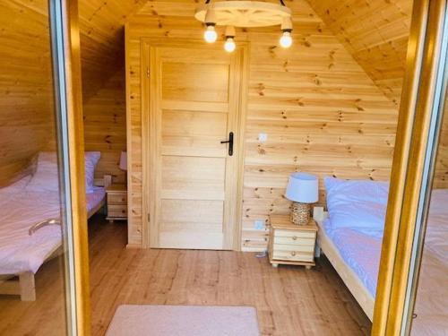 a room with two beds in a wooden cabin at KALINOWY SAD DOMKI z JACUZZI i SAUNĄ in Mikołajki