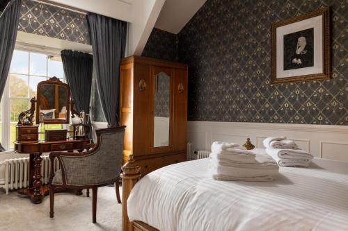 a bedroom with a bed and a desk and a mirror at Plas Dinas Country House in Caernarfon