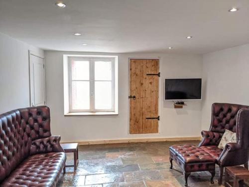 a living room with two leather chairs and a television at Trois Mousquetaires Gîte in Saint-Dizier-Leyrenne