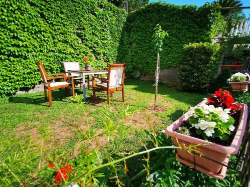 un giardino con tavolo, sedie e fiori di Apartments Vila Andja a Sveti Stefan