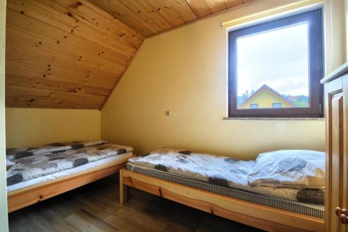 Duas camas num quarto com uma janela em Słoneczne domki 2 em Istebna