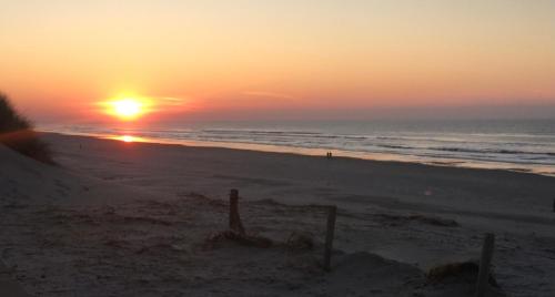a sunset on a beach with the ocean at Familie Metz in Buren