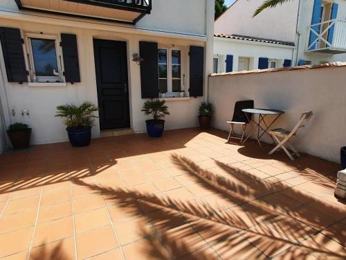 un patio avec une table et des chaises devant une maison dans l'établissement Le Phare - Gîte de mer Boyardville, à Boyardville