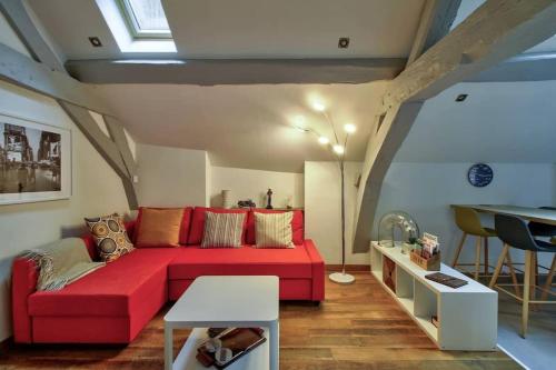 a living room with a red couch and a table at La Mansarde : Cosy et Charme au Centre Historique in Dijon