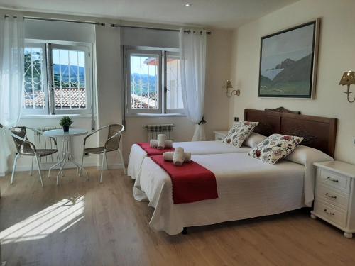 a bedroom with a bed and a table and windows at Hotel Alvaro frente Palacio-Museo Selgas in Cudillero