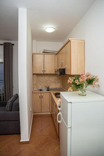 a small kitchen with wooden cabinets and a vase of flowers at Hotel SUNSET GL in Vlorë