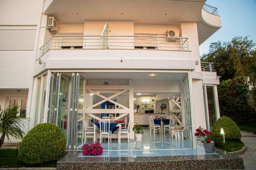 a house with glass doors and tables and chairs at Hotel SUNSET GL in Vlorë