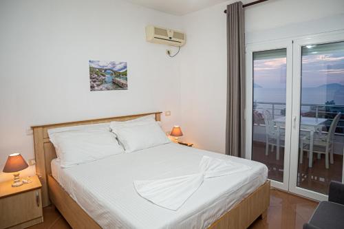 a bedroom with a bed and a balcony with a table at Hotel SUNSET GL in Vlorë