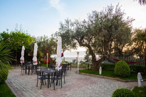 a patio with tables and chairs with umbrellas at Hotel SUNSET GL in Vlorë