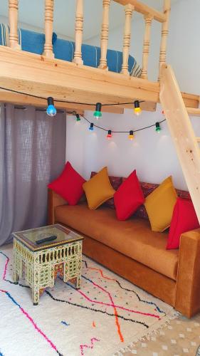 a living room with a couch with red and yellow pillows at Art riad mazighen in El Jadida