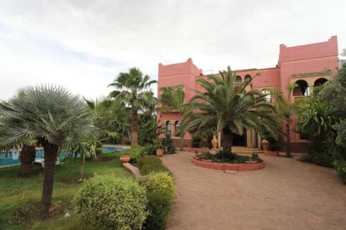 a building with palm trees in front of a courtyard at Equi Palace & SPA Near Aeroport in Berrechid