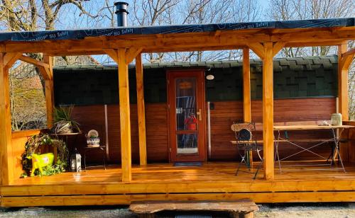 eine Hütte mit einer Holzterrasse mit einem Pavillon in der Unterkunft Irenes Tinyhouse in Markt Nordheim
