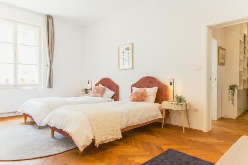 Habitación con 2 camas, paredes blancas y suelo de madera. en Top location CITY CENTRE CONDO in historic building with free garage PARKING, en Liubliana