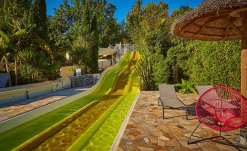- un toboggan dans un complexe avec 2 chaises et une aire de jeux dans l'établissement Mobil home neuf, à Biscarrosse