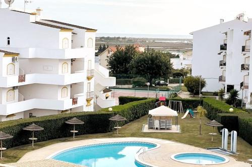 タヴィラにあるTavira Nature Houseの建物の前にスイミングプールがあるアパートメント