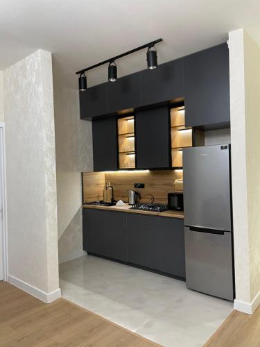 uma cozinha com armários pretos e um frigorífico de aço inoxidável em Apartment D. Digomi em Tbilisi