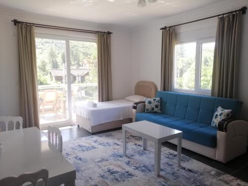 een woonkamer met een blauwe bank en een bed bij Olympos Apart in Olympos